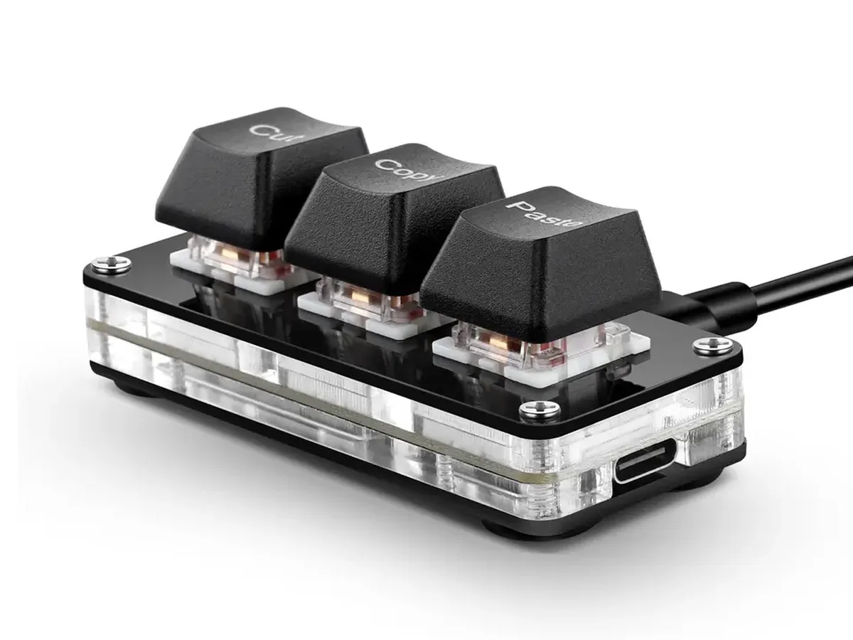 Le SayoDevice CM3 noir : trois touches marquées Cut, Copy et Paste sur un boîtier transparent, avec le port USB-C sur le côté.